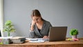 A stressed and frustrated Asian businesswoman sits at her desk in her office