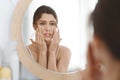 Stressed girl touching her skin and looking at mirror Royalty Free Stock Photo