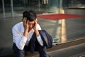 Stressed and hopeless Asian businessman sits on the stairs outside the company building Royalty Free Stock Photo