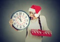 Stressed in a hurry woman wearing santa claus hat holding clock gift box Royalty Free Stock Photo