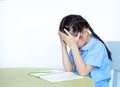 Stressed little girl in school uniform sitting at desk isolated over white background. Schoolgirl unhappy doing homework. Student Royalty Free Stock Photo