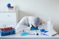 Stressed male doctor sitting tired at his desk. Mid adult male doctor working long hours in protective clothes. Covid-19 Royalty Free Stock Photo