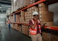 Stressed male worker talking on cellular device to boss while holding digital tablet in warehouse. Royalty Free Stock Photo