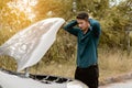 Stressed man trying to check a car engine, looking inside open bonnet. Car broken concept Royalty Free Stock Photo