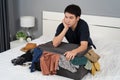 Stressed man trying to close overfilled suitcase on bed Royalty Free Stock Photo