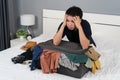 Stressed man trying to close overfilled suitcase on bed Royalty Free Stock Photo