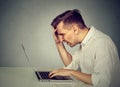 Stressed man working on laptop sitting at table