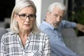 Stressed mature wife feeling frightened with annoyed older husband behind Royalty Free Stock Photo