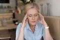 stressed mature woman with closed eyes having headache while