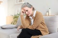 Stressed middle aged woman sit on sofa in living room, lost in thought