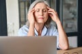 Stressed senior 60s aged massaging head at home office, suffering on workplace. Royalty Free Stock Photo