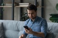 Stressed millennial man looking at cellphone screen.