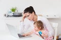 Stressed Mother With Child Using Laptop At Home Royalty Free Stock Photo