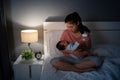 stressed mother trying to feeding milk bottle to her crying newborn baby on bed at night Royalty Free Stock Photo