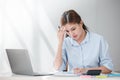 Stressed out Asian Business woman using calculator and laptop for doing math finance on an office desk, tax, report Royalty Free Stock Photo