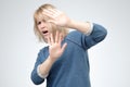 Stressed out woman keeping hands in stop gesture, trying to defend herself as if saying Stop that