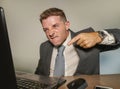 Stressed and overwhelmed businessman in suit and tie working at office laptop computer desk screaming desperate and upset in