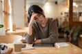 A stressed Asian woman is concerned about her project's deadline while working remotely at a cafe Royalty Free Stock Photo
