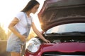 Stressed pregnant woman fixing broken car on city street Royalty Free Stock Photo