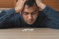 Stressed, sad asian young man, male holding medicine, lying on table. Close up hand of abuse overdose pills and addict. Sick pain