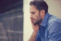 Stressed sad business man sitting outdoors holding head with hand looking down