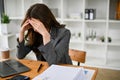 Stressed and sad Asian businesswoman sitting at her desk, suffering from headache Royalty Free Stock Photo