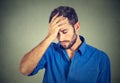 Stressed sad young man looking down on gray wall background