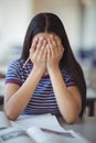 Stressed schoolgirl doing covering her face in classroom Royalty Free Stock Photo