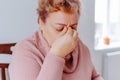 Stressed Senior Woman at Home Feeling Sad and Achy While Reading with Glasses