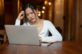 A stressed Asian woman is staring at her laptop screen with an unsatisfied face, having a problem Royalty Free Stock Photo