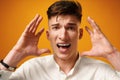 Stressed shouting young man holding hands near his head Royalty Free Stock Photo