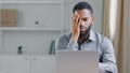 Stressed sick African American ethnic bearded man suffer with headache pain office worker businessman with laptop Royalty Free Stock Photo