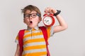 Stressed surprised and angry kid yawn and holding alarm clock. Change time. Pupil with bag and in glasses. Hurry up Royalty Free Stock Photo