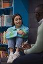 Stressed teenage girl talking to mental health therapist in college library Royalty Free Stock Photo