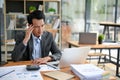 A stressed and thoughtful Asian businessman is working at his desk in the office Royalty Free Stock Photo