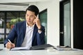 Stressed Asian businessman examining financial reports, working at his desk Royalty Free Stock Photo