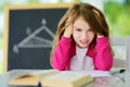 Stressed schoolgirl studying with a pile of books on her desk. Young girl doing her homework. Education and distance learning for