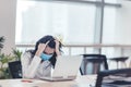 Stressed and tired young businesswoman wear face mask working in office