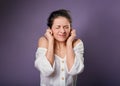 Stressed unhappy casual woman closed ears the fingers because not want the hear any sounds and noise on purple background. Closeup