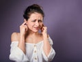 Stressed unhappy casual woman closed ears the fingers because not want the hear any sounds and noise on purple background. Closeup