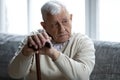 Stressed unhappy older mature grandfather holding hands on wooden stick.