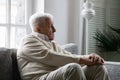 Stressed unhappy older retired man sitting alone on couch.