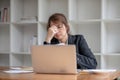 Stressed and upset Asian female office worker looking at her laptop screen, pensive Royalty Free Stock Photo