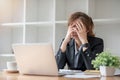 Stressed and upset Asian female office worker looking at her laptop screen, pensive Royalty Free Stock Photo