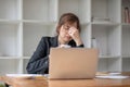 Stressed and upset Asian female office worker looking at her laptop screen, pensive Royalty Free Stock Photo