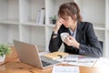 Stressed and upset Asian female office worker looking at her laptop screen, pensive Royalty Free Stock Photo