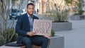 Stressed upset fired manager male in business suit sitting in city with poster need work searching job hopeless ethnic Royalty Free Stock Photo