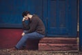 Stressed and upset young man sitting outside holding head with a hand looking down. Human emotion feelings, sad bearded Royalty Free Stock Photo