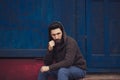 Stressed and upset young man sitting outside holding head with a hand looking down. Human emotion feelings, sad bearded Royalty Free Stock Photo