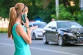 Stressed woman driver talking on mobile phone on street side calling for emergency service after car accident. Road Royalty Free Stock Photo